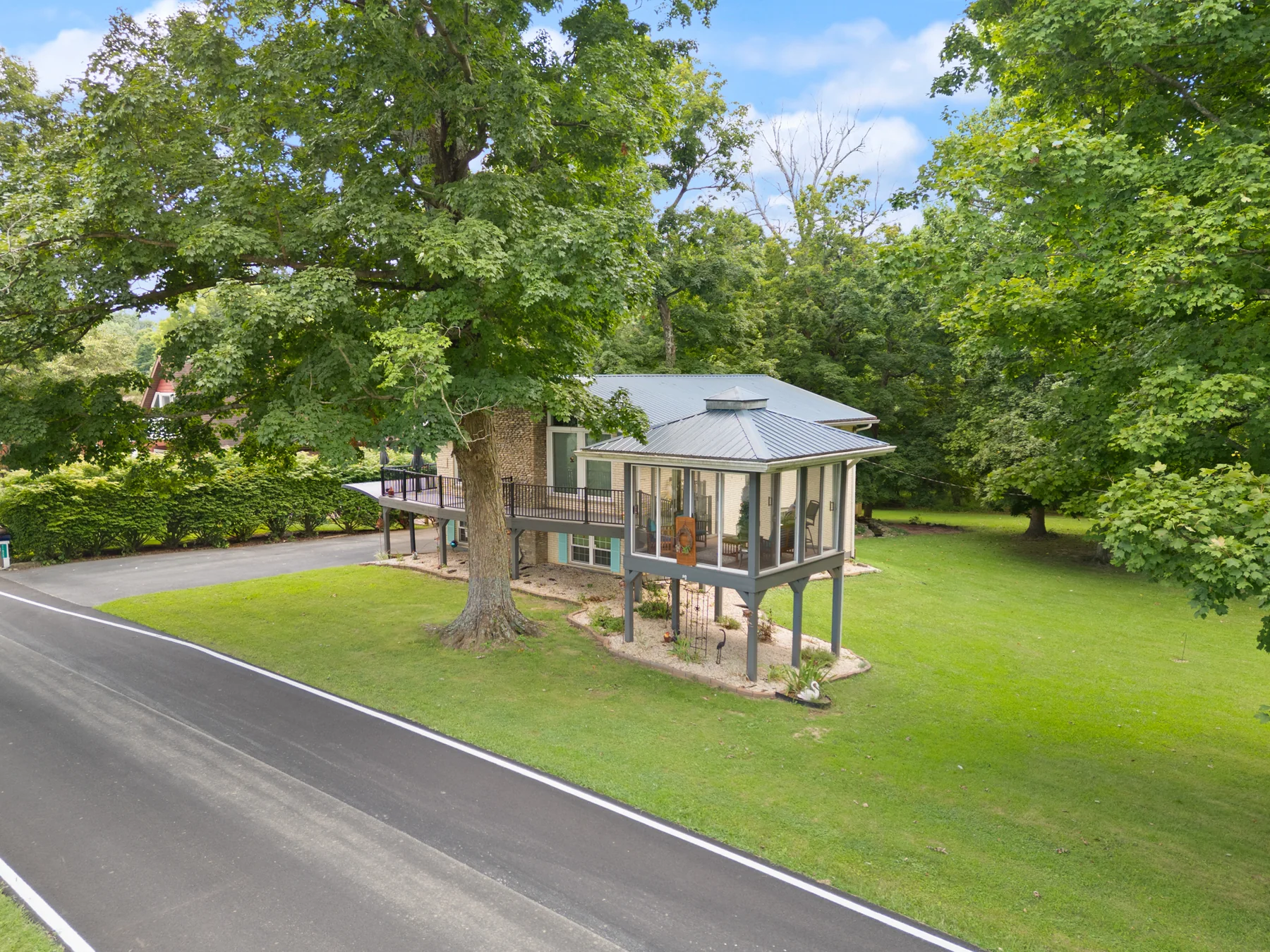 Aerial view of the home, mature trees, lawn, and Ohio River setting