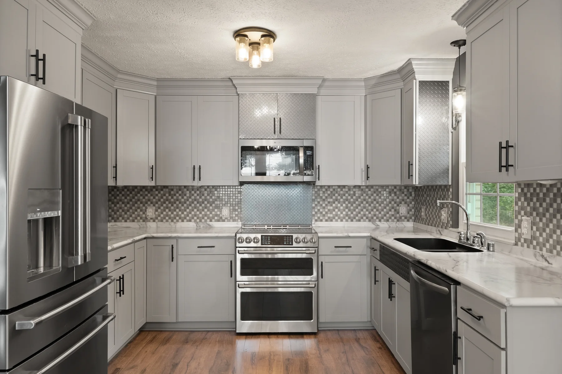 Updated kitchen with gray cabinetry and stainless steel appliances