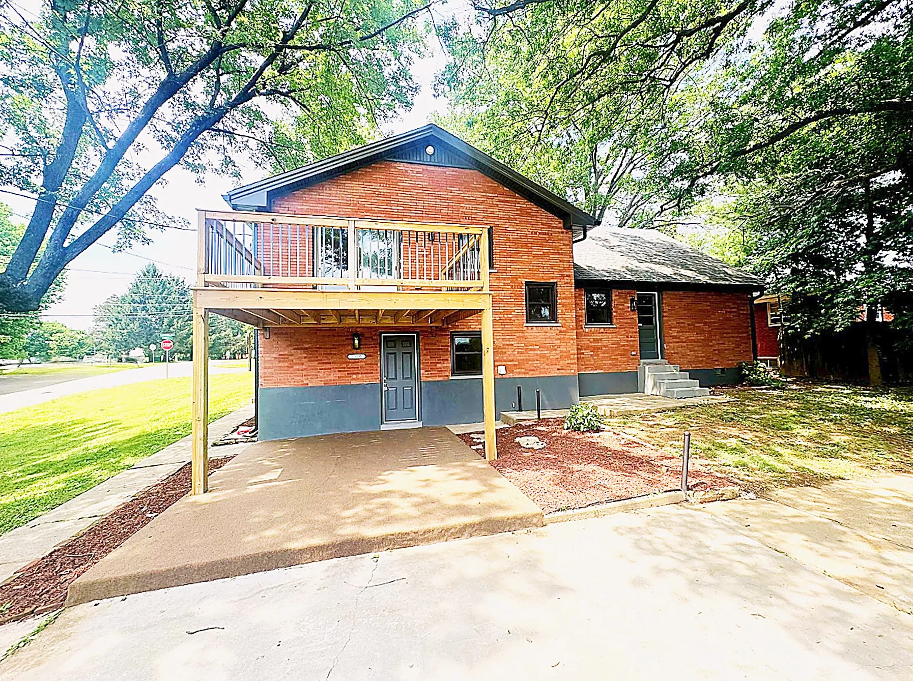 Rear three-quarter view showing the elevated wood deck and mature trees