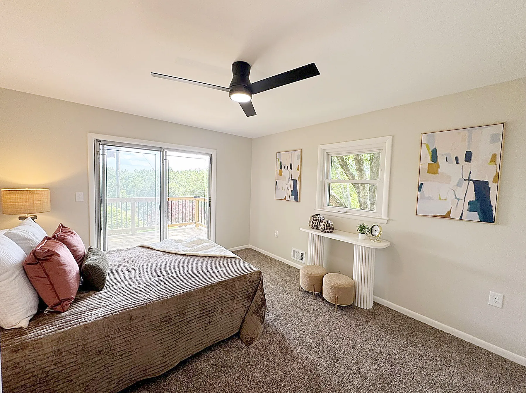 Second-floor primary bedroom with access to a large wooded deck overlooking the backyard