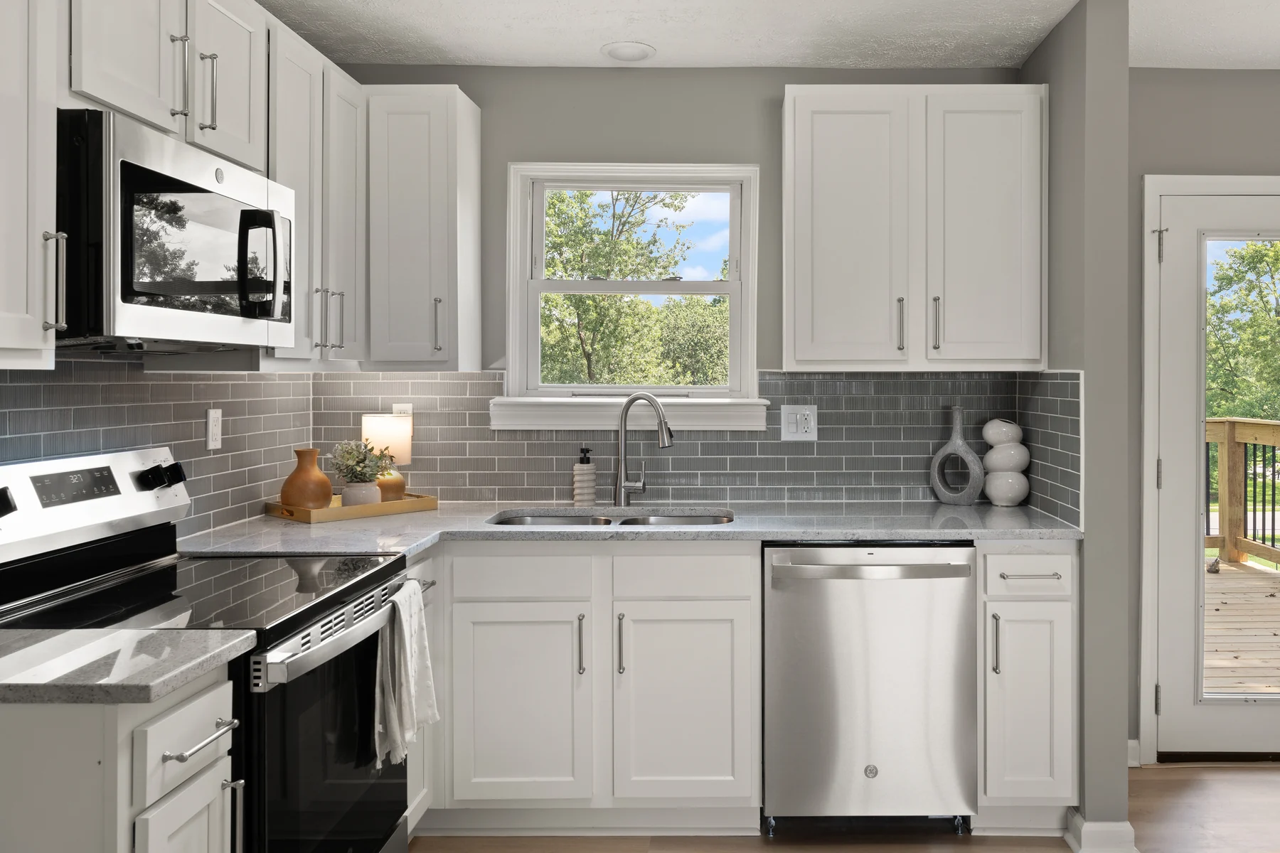 Updated white kitchen with gray tile backsplash and stainless appliances