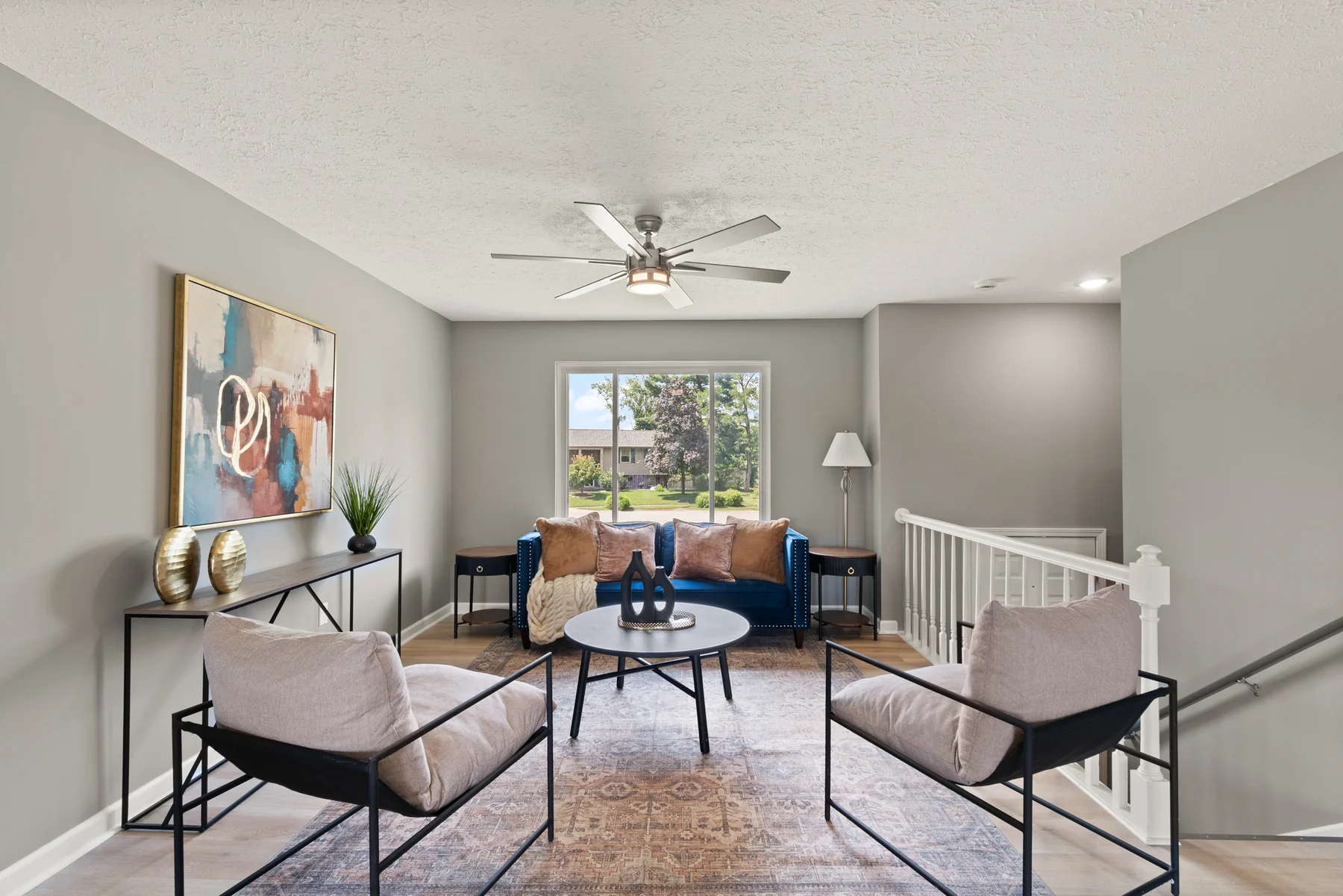 Refreshed living room with neutral finishes, modern ceiling fan, and natural light