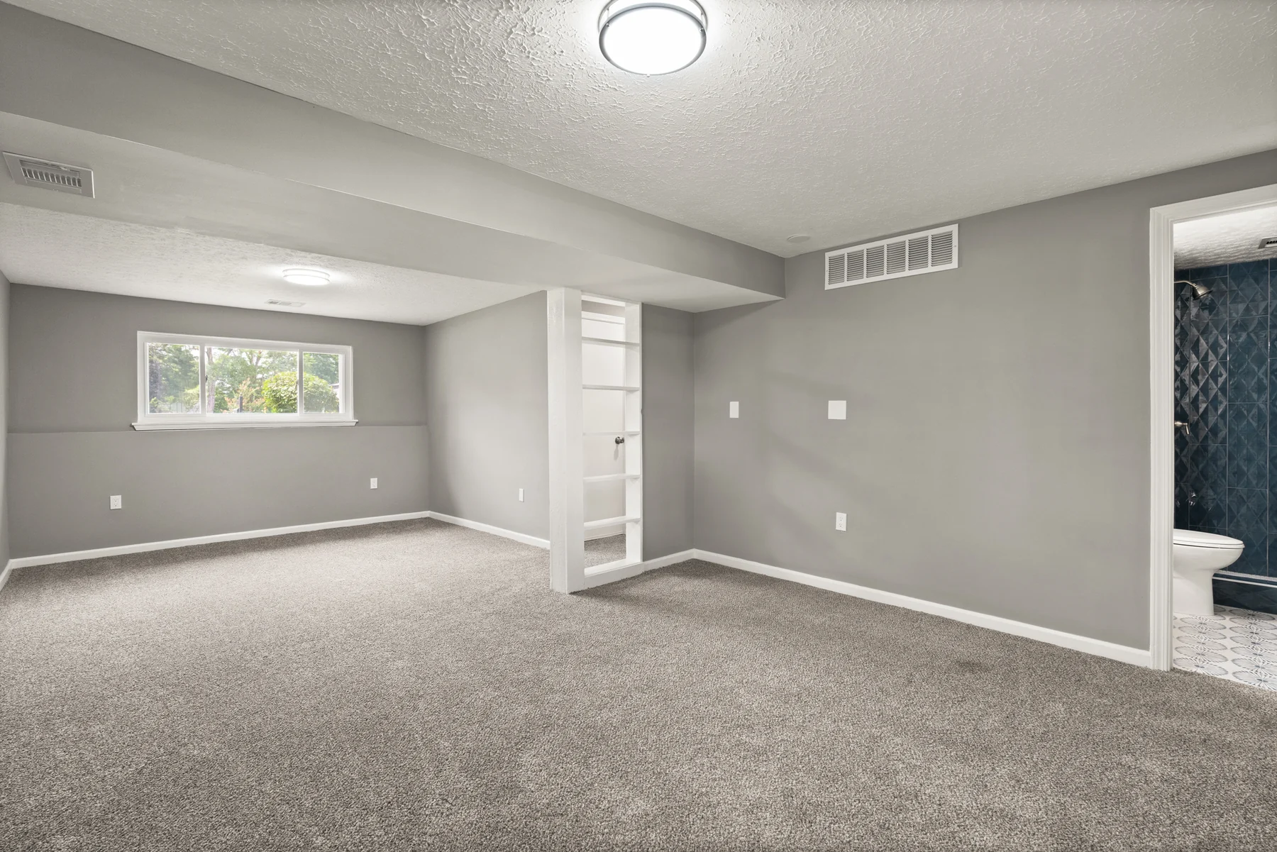 Finished lower-level family room with built-in shelving and soft carpeting