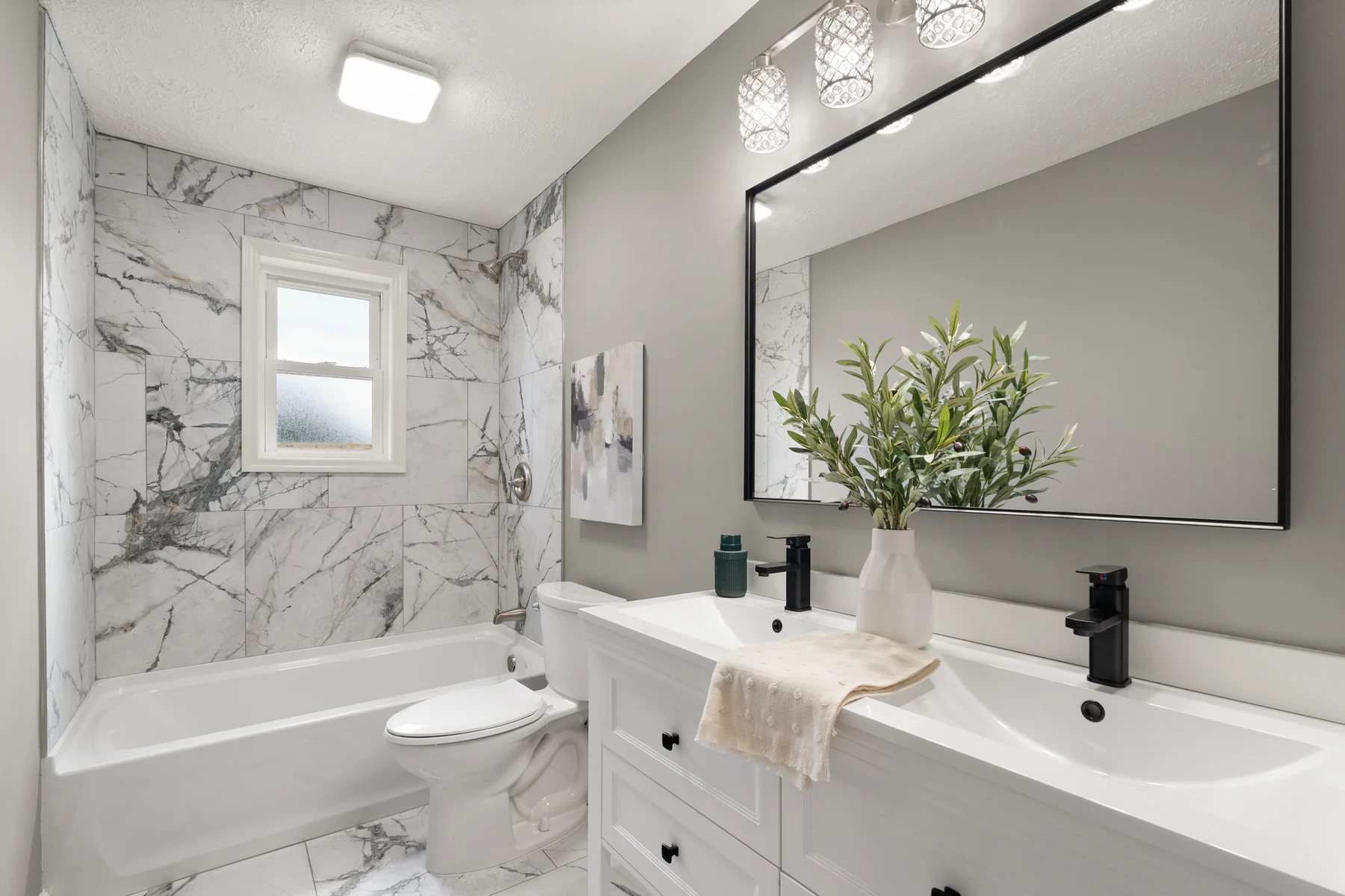 Updated full bathroom with double vanity, ceramic tile, and tub surround