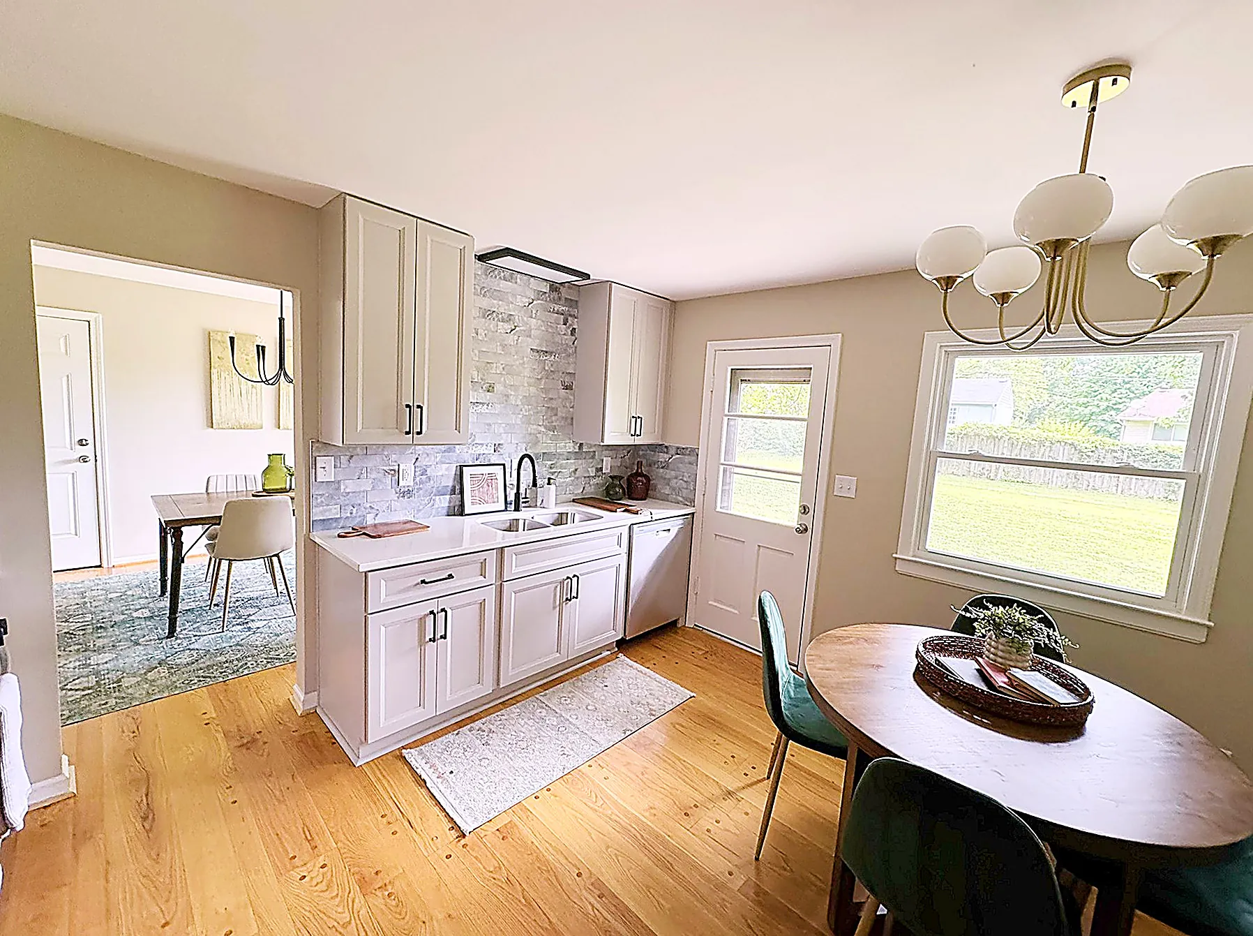 Wide view of the eat-in kitchen with white shaker cabinets, granite counters, and a sightline through to the formal dining room