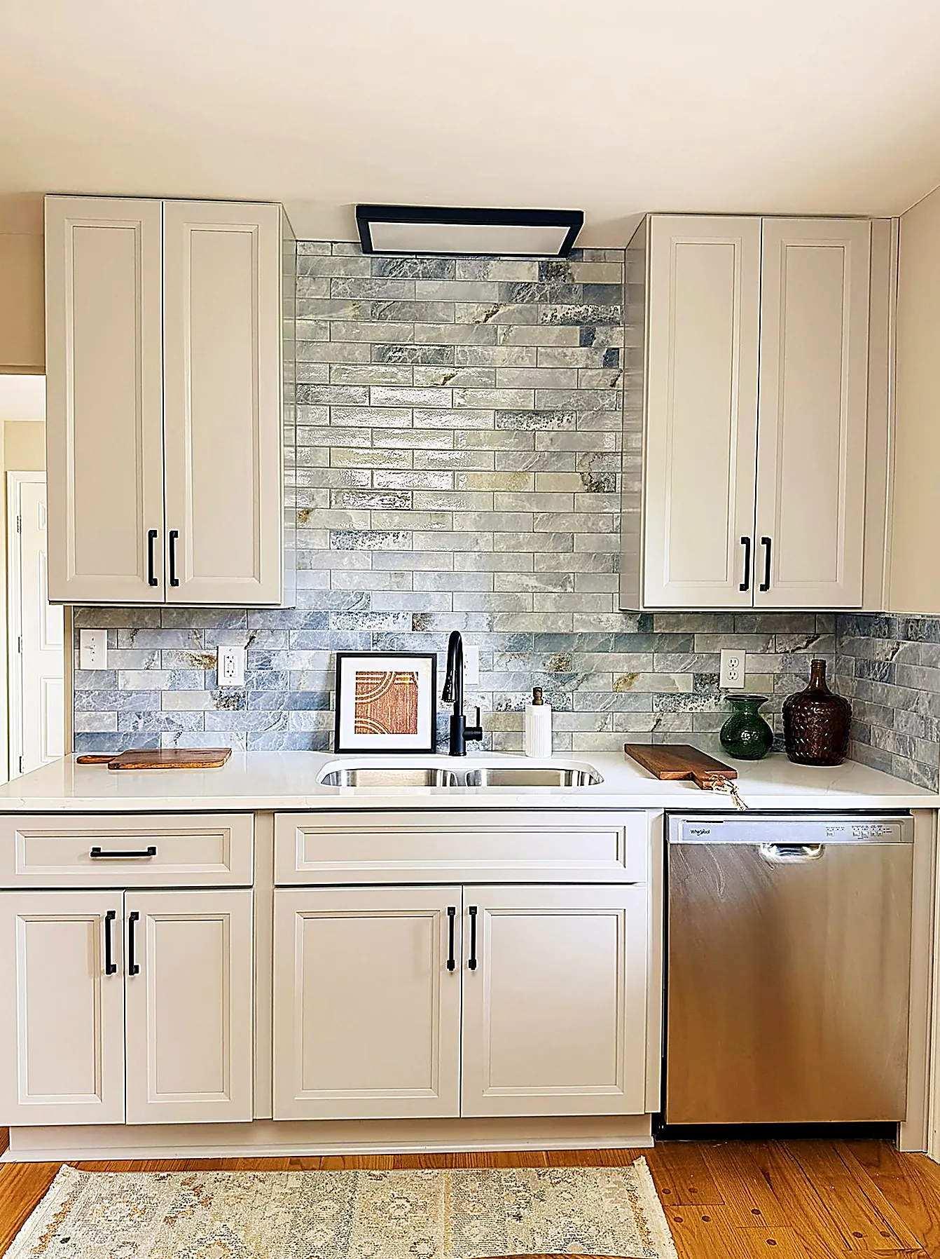 Kitchen detail showing stone-look tile backsplash and cabinetry