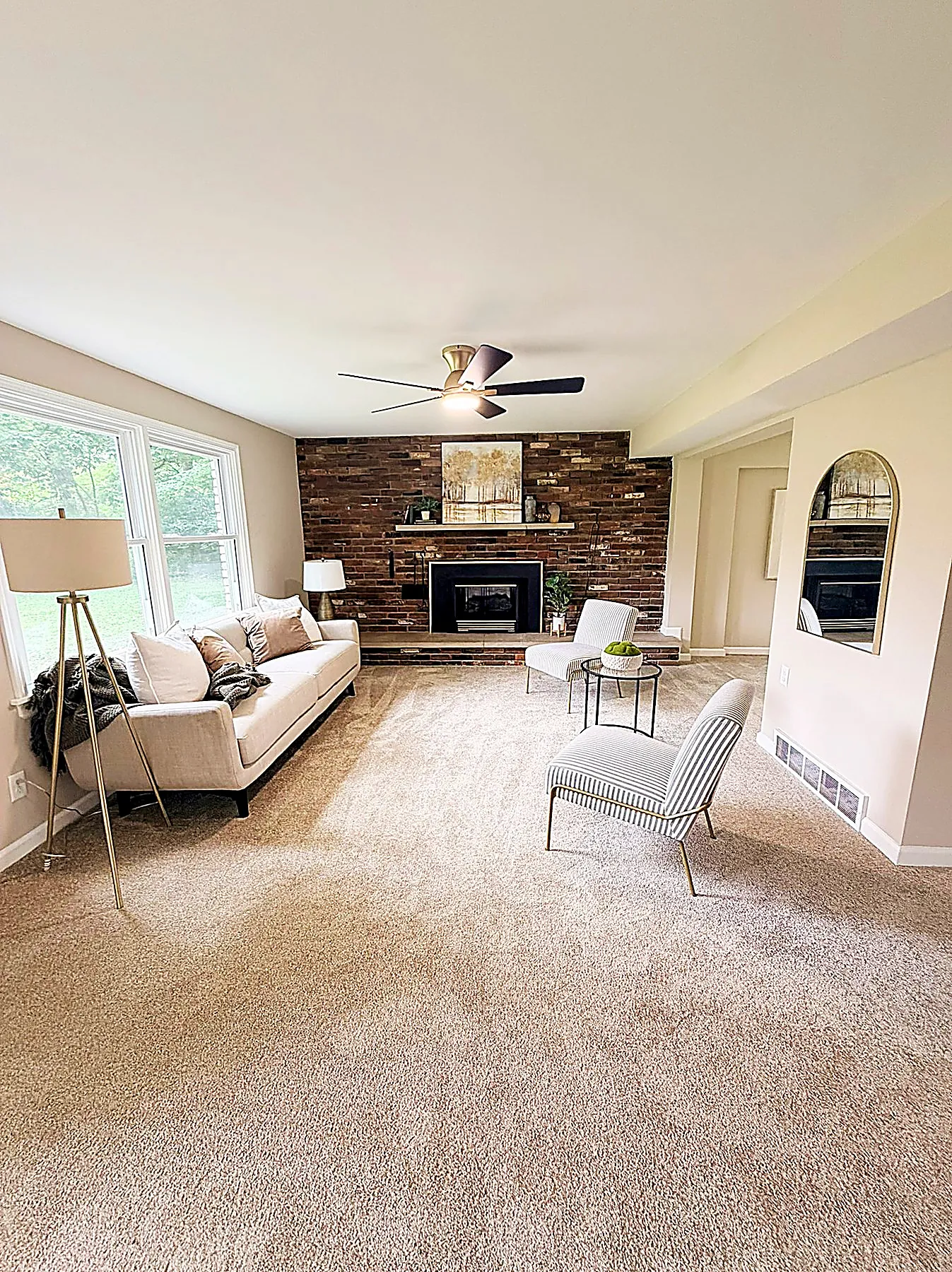 Family room with a natural red-brick fireplace, cream sofa, and soft carpet underfoot