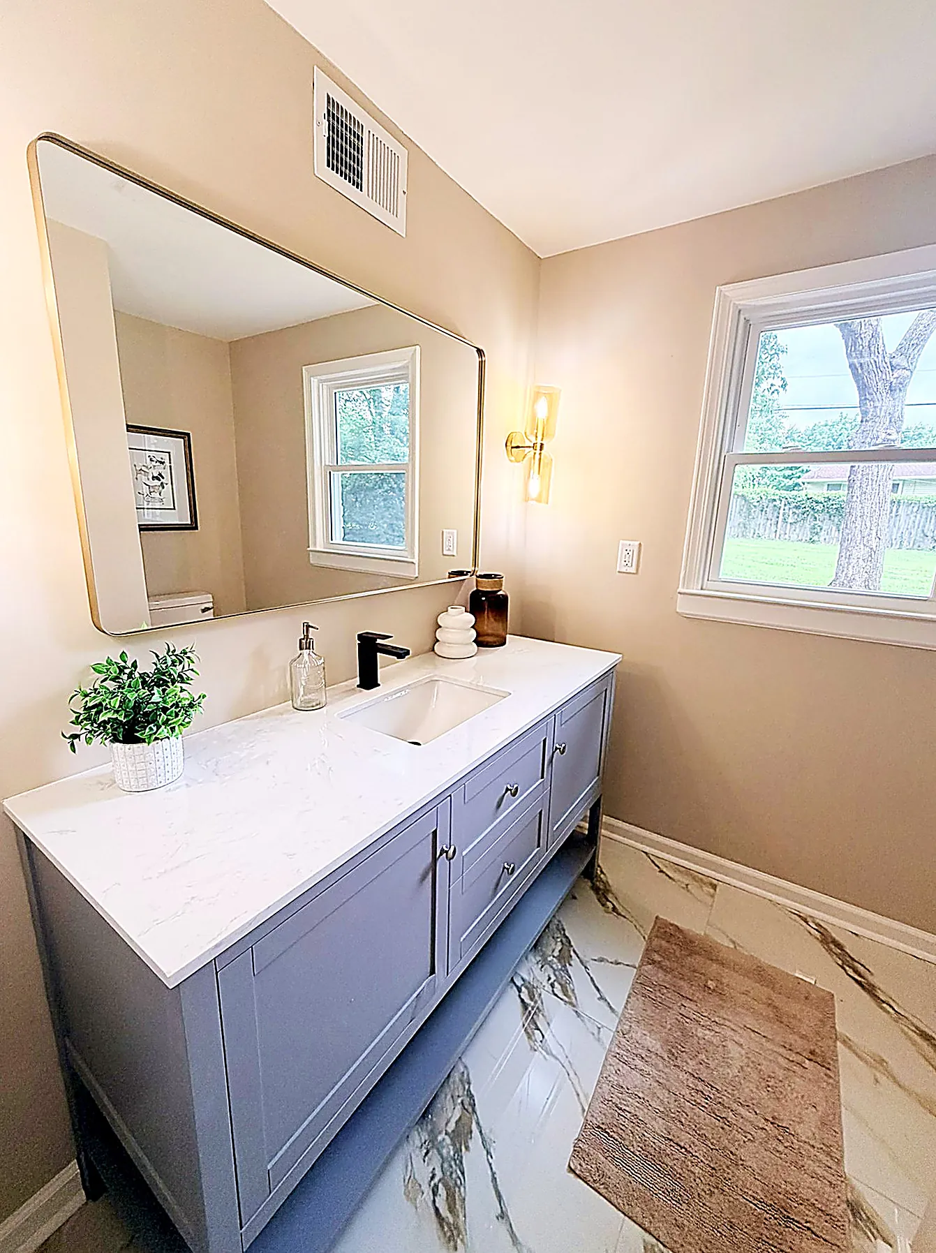 Modern bathroom with a double floating vanity, large mirror, and sconces