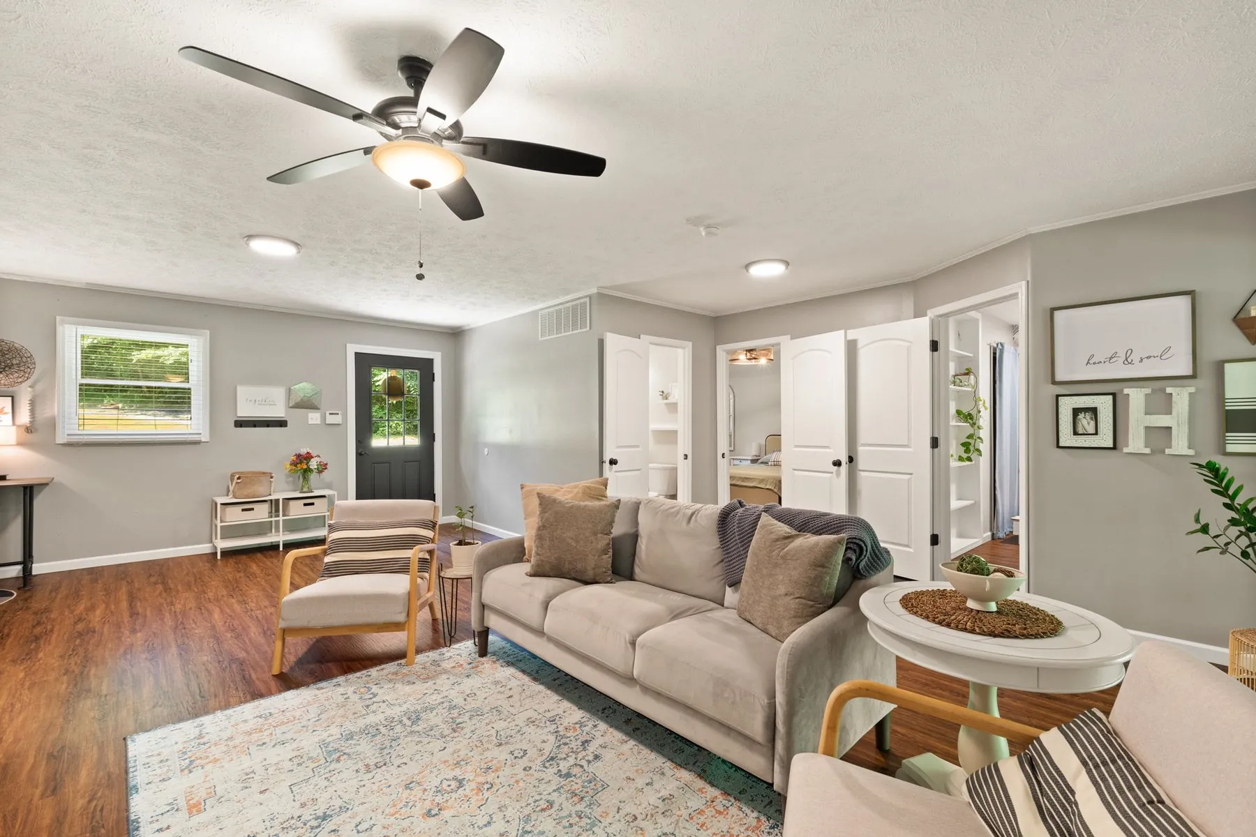 Living room with laminate flooring, ceiling fan and windows to the woods