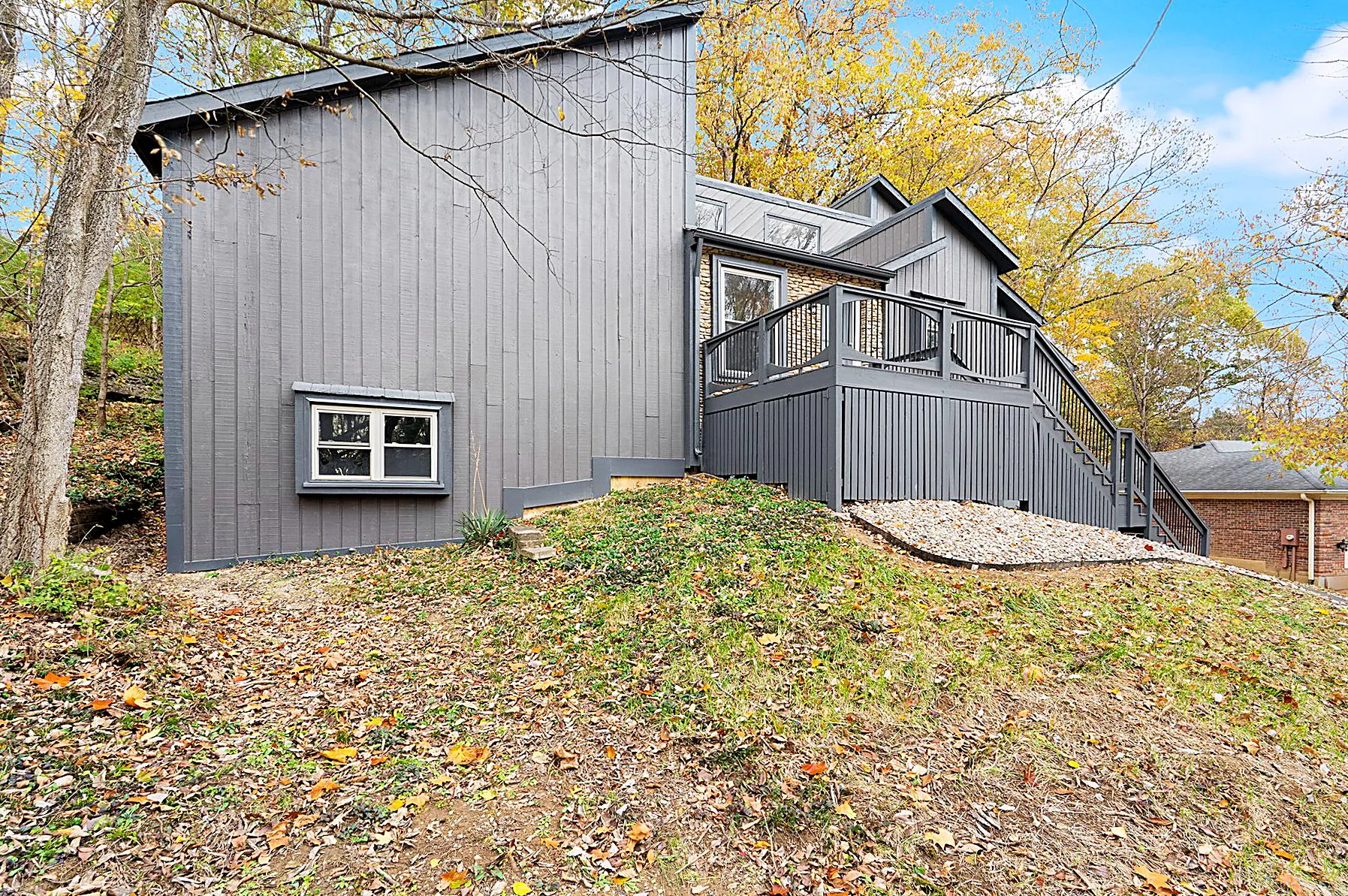 Rear exterior of the home framed by mature trees on the wooded lot