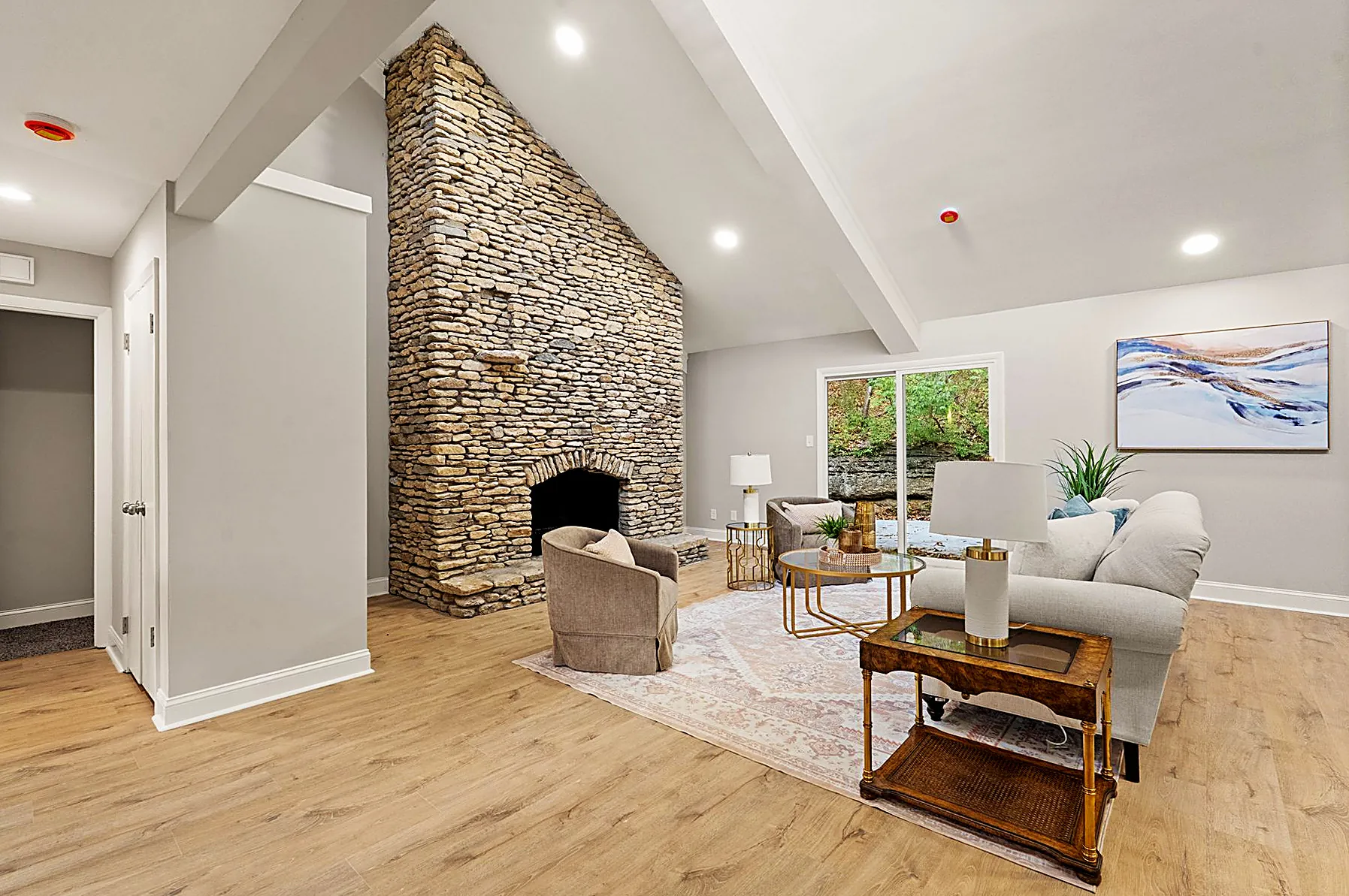 Living room with a dramatic floor-to-ceiling stone fireplace rising into vaulted, open-beam ceilings