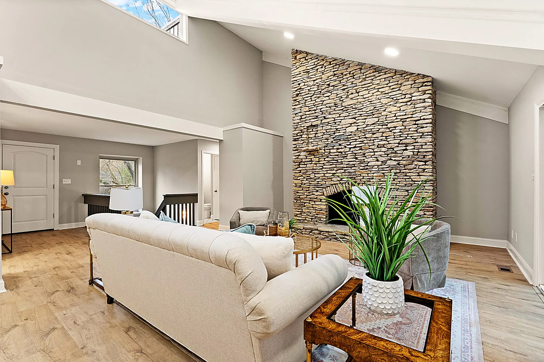 Open living area beneath vaulted beams with the floor-to-ceiling stone fireplace