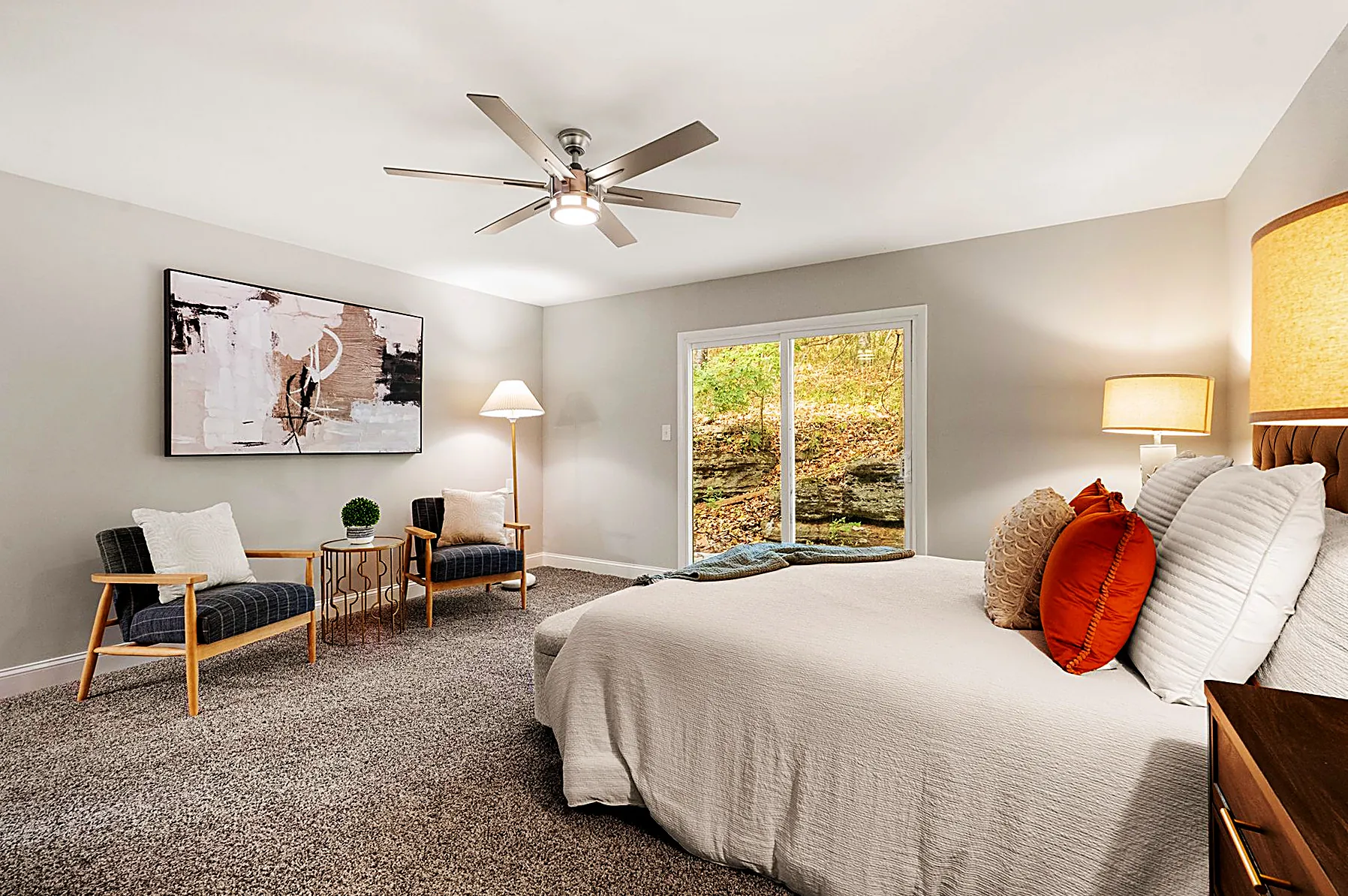 Main-level primary suite with a staged bed and direct access to the private rear patio