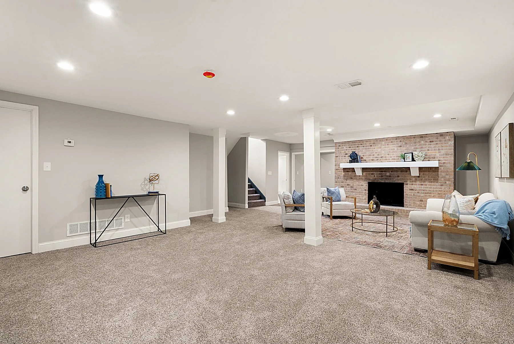 Finished walkout lower-level family room centered on a brick fireplace