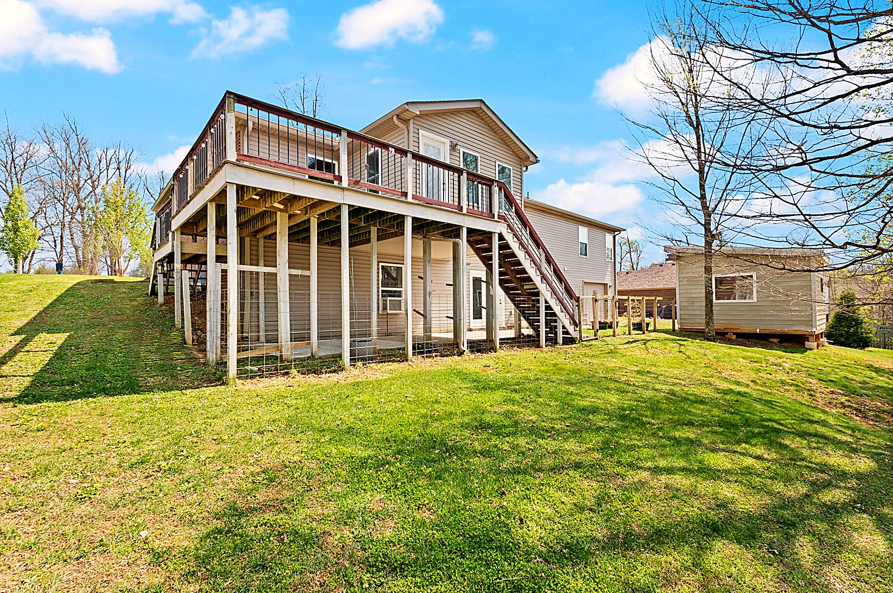 Rear of the home rising two stories with an elevated deck overlooking the wooded 1.24-acre lot