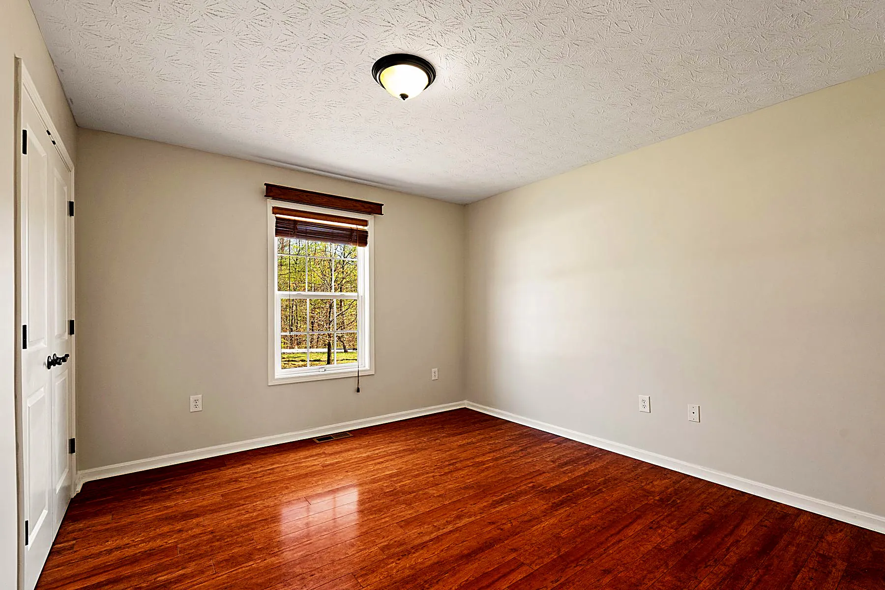 Main-level bedroom with hardwood flooring and natural light