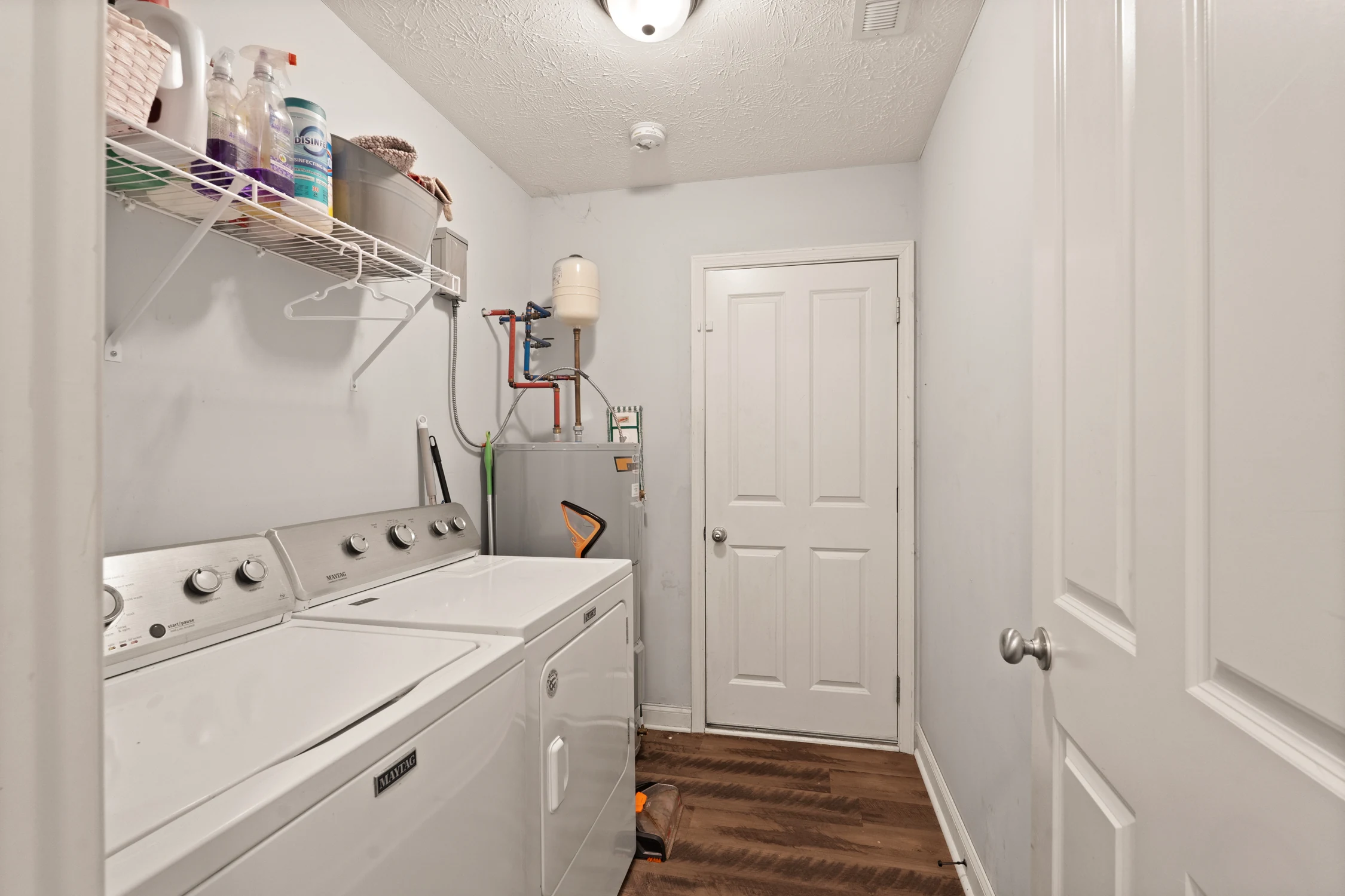 Main-level laundry room with washer, dryer, shelving, and utility access