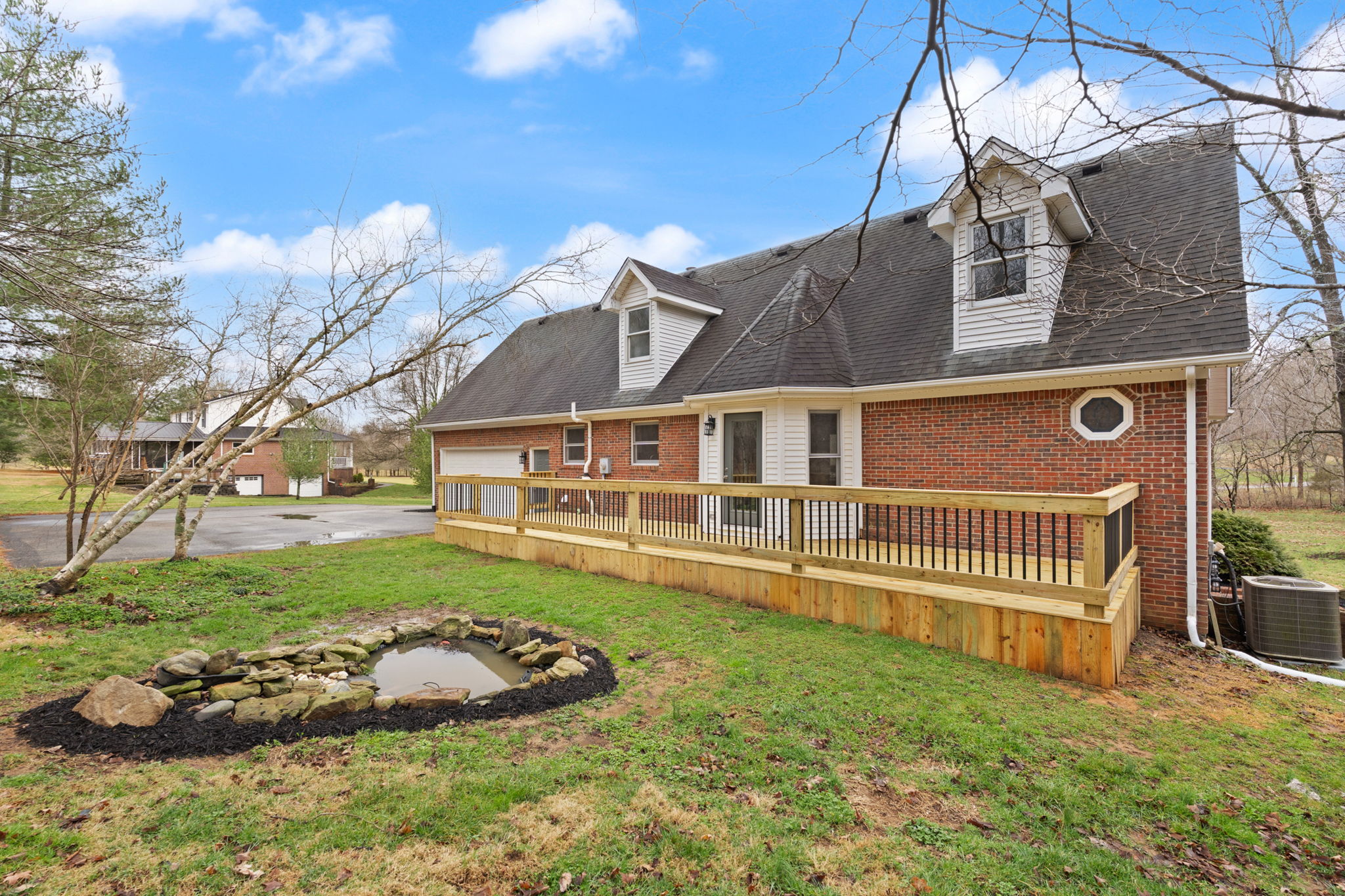 Rear elevation showing new wood deck, stone pond, dormers