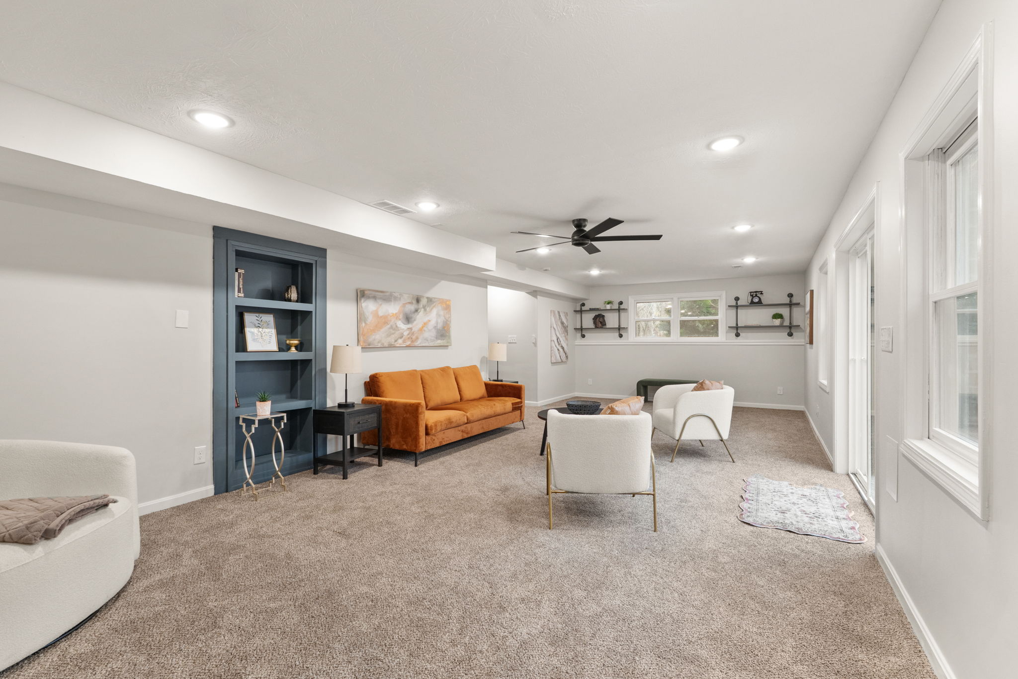 Basement family room with navy built-in bookcase, styled shelves