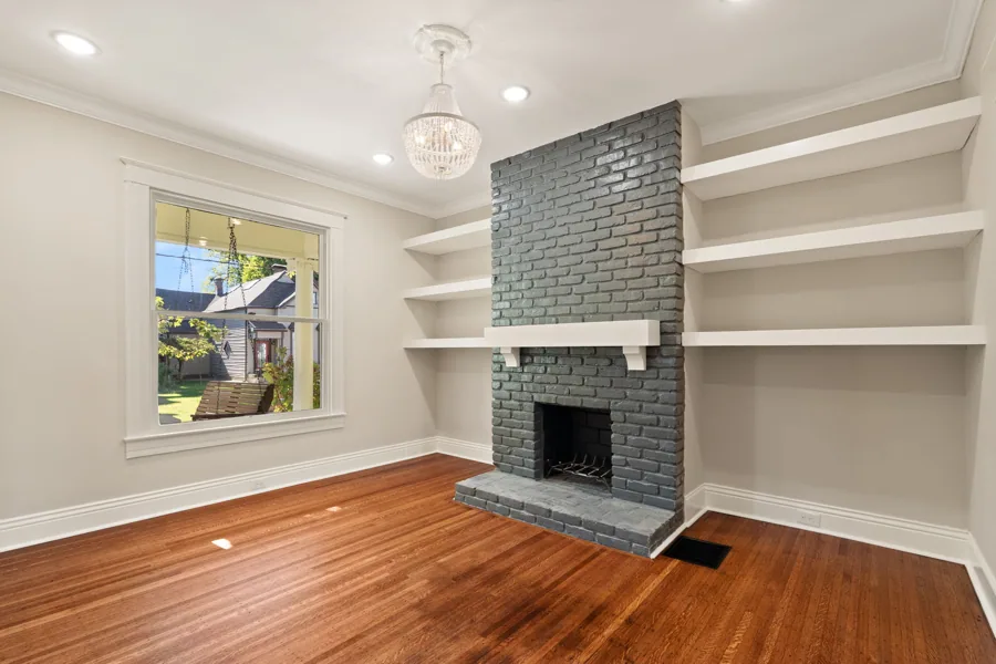 Living room with a fireplace, built-ins and a front-facing window. 1839 Sherwood Avenue, Louisville, Kentucky.