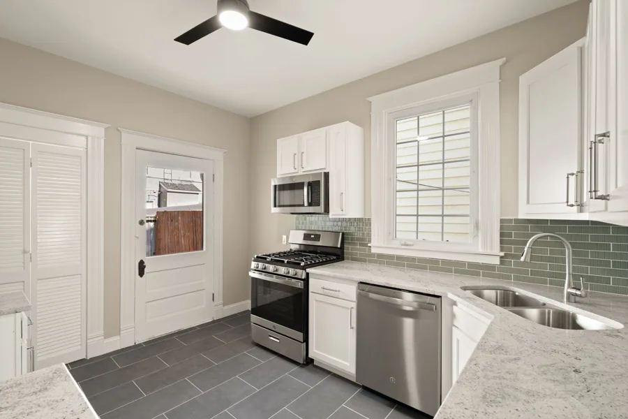 White cabinetry, granite countertops, tile floors and a subway tile backsplash. 1839 Sherwood Avenue, Louisville, Kentucky.